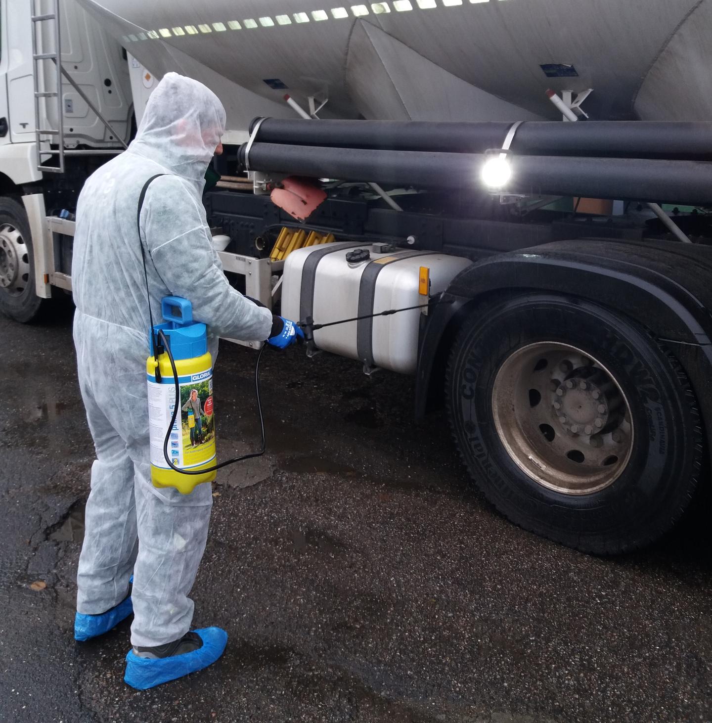 Als Hygienemaßnahmen sprüht ein Mann in einem Schutzanzug einen Lastwagen ein.