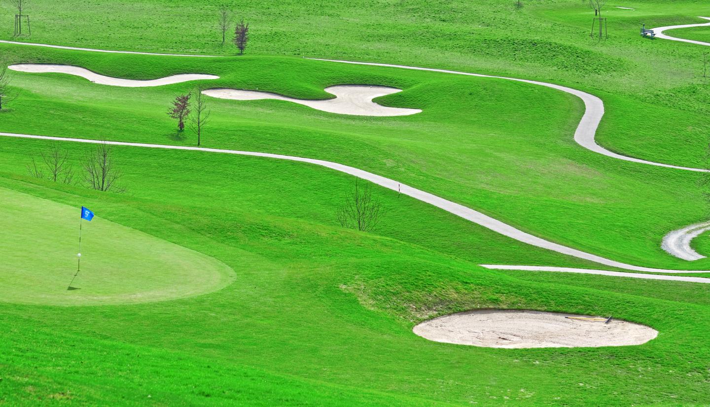 Ein sonniger Golfplatz mit grünen Fairways und Bunkern.