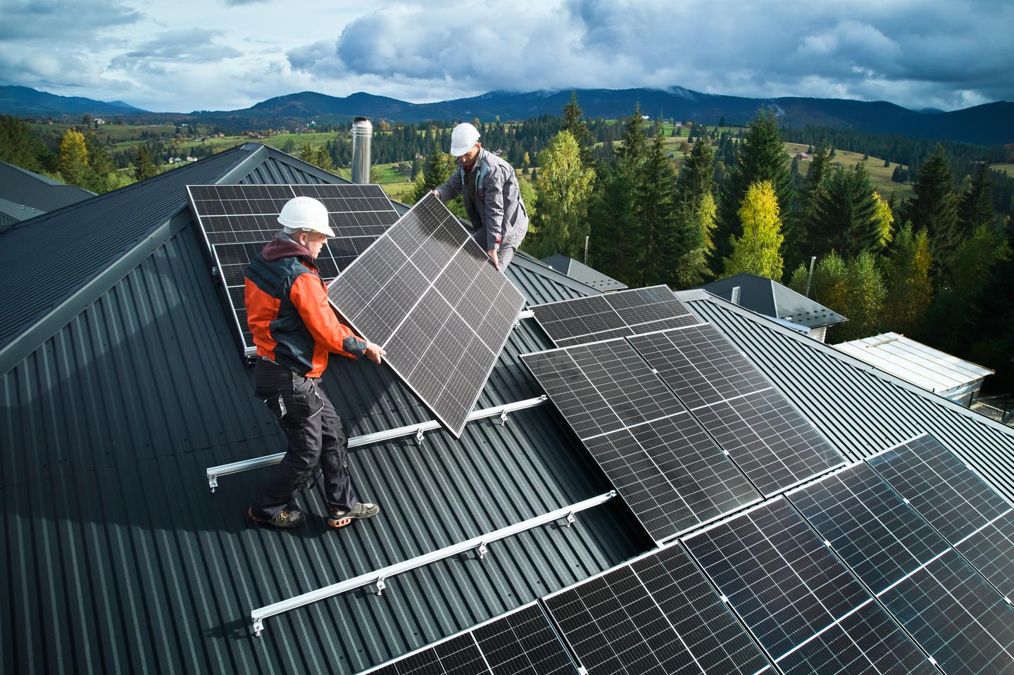 Solarpanels werden von zwei Männern auf einem Dach montiert