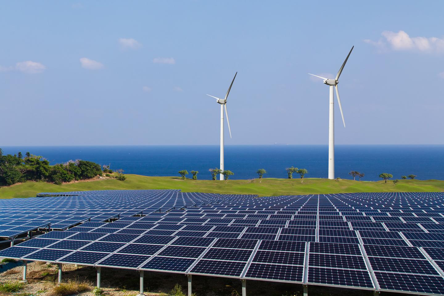 Ein Feld aus Photovoltaik mit Windenergie an der Küste