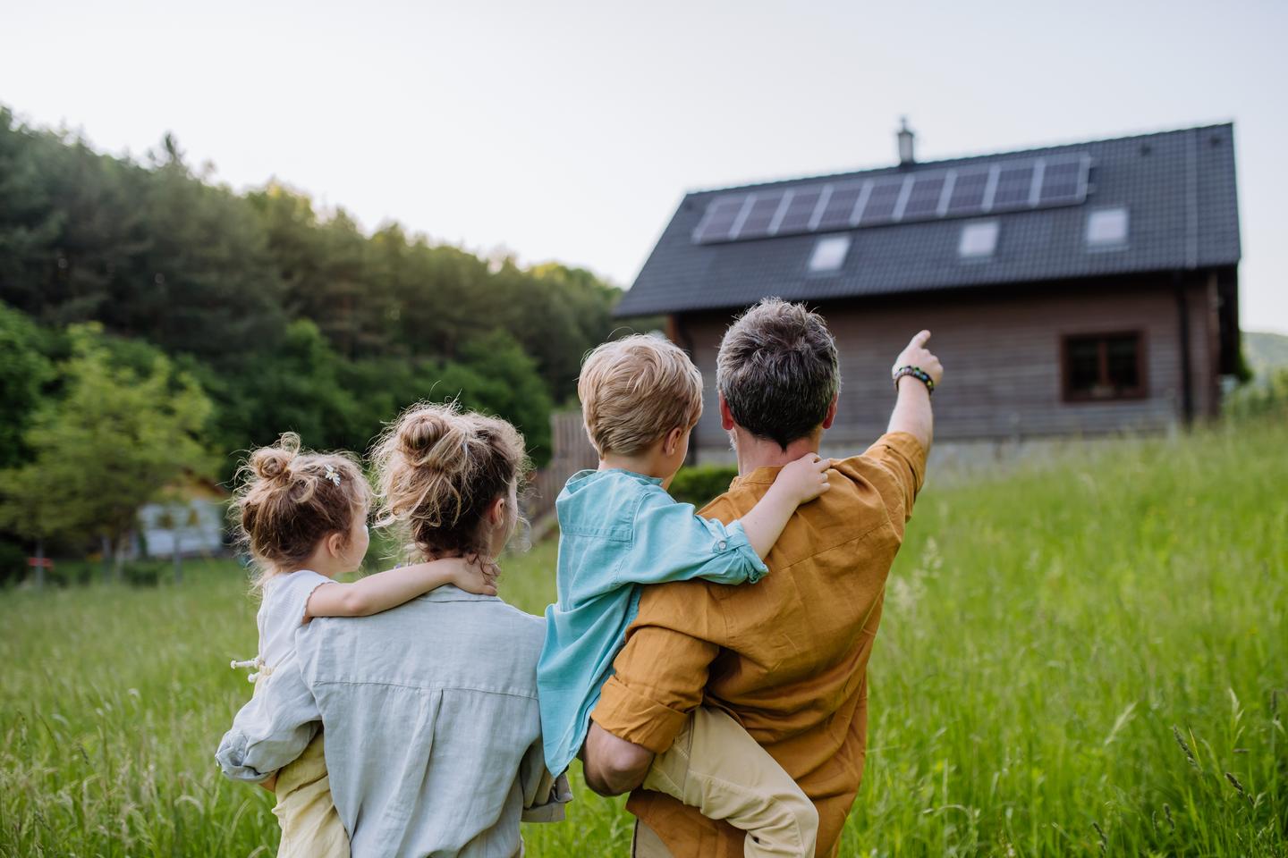 Familie guckt auf ein Haus mit Solar