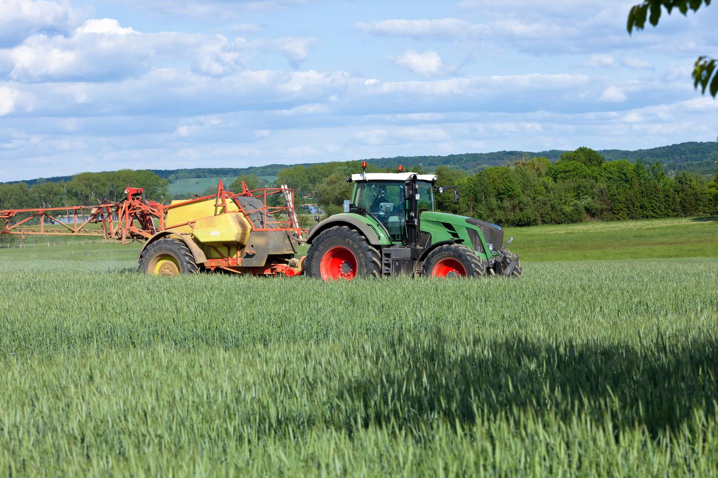 Traktor bringt Pflanzenschutzmittel auf Getreidefeld aus, um die Ernte vor Schädlingen und Krankheiten zu schützen.
