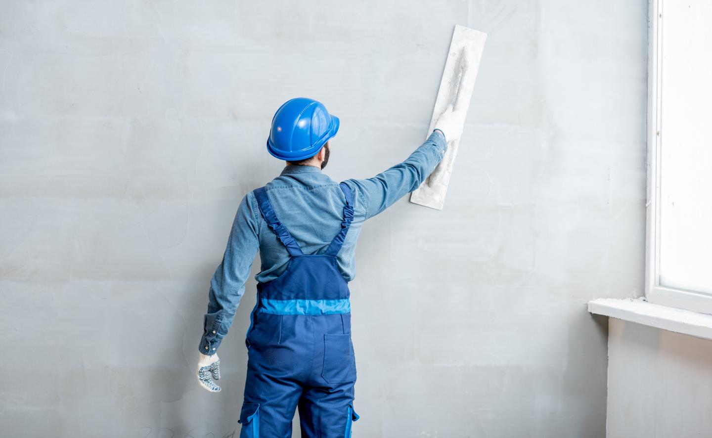 Bauarbeiter verstricht Putz an einer Wand